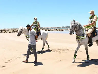 Sejumlah tentara berkuda yang berpatroli di sebuah pantai mengawal seorang pria agar meninggalkan lokasi tersebut di Sale, Maroko, Minggu (14/6/2020). Maroko pada 14 Juni 2020 mengumumkan 101 infeksi baru COVID-19, menambah jumlah kasus terkonfirmasi di negara tersebut menjadi 8.793. (Xinhua/Chadi)
