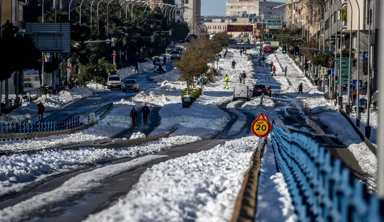 Orang-orang berjalan melewati salju di Madrid, Spanyol, Senin (11/1/2021). Ibu kota Spanyol itu berusaha bangkit kembali setelah menghadapi badai salju terburuk dalam 50 tahun terakhir yang melumpuhkan sebagian besar wilayah Spanyol tengah selama akhir pekan. (AP Photo/Manu Fernandez)