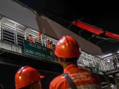 Petugas dari Dinas Pemadam Kebakaran berusaha melepaskan papan reklame yang terpasang di dinding JPO kawasan Salemba, Jakarta, Rabu (26/10) malam. Pembongkaran dilakukan lantaran  papan reklame itu diketahui tidak berizin. (Liputan6.com/Faizal Fanani)