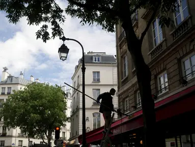 Seorang pekerja membersihkan tenda sebuah restoran, di Paris, Senin (17/5/2021). Teras luar kafe dan restoran Prancis akan diizinkan untuk dibuka kembali pada 19 Mei bersama dengan museum, bioskop, teater, dan ruang konser dalam kondisi tertentu. (AP Photo/Thibault Camus)