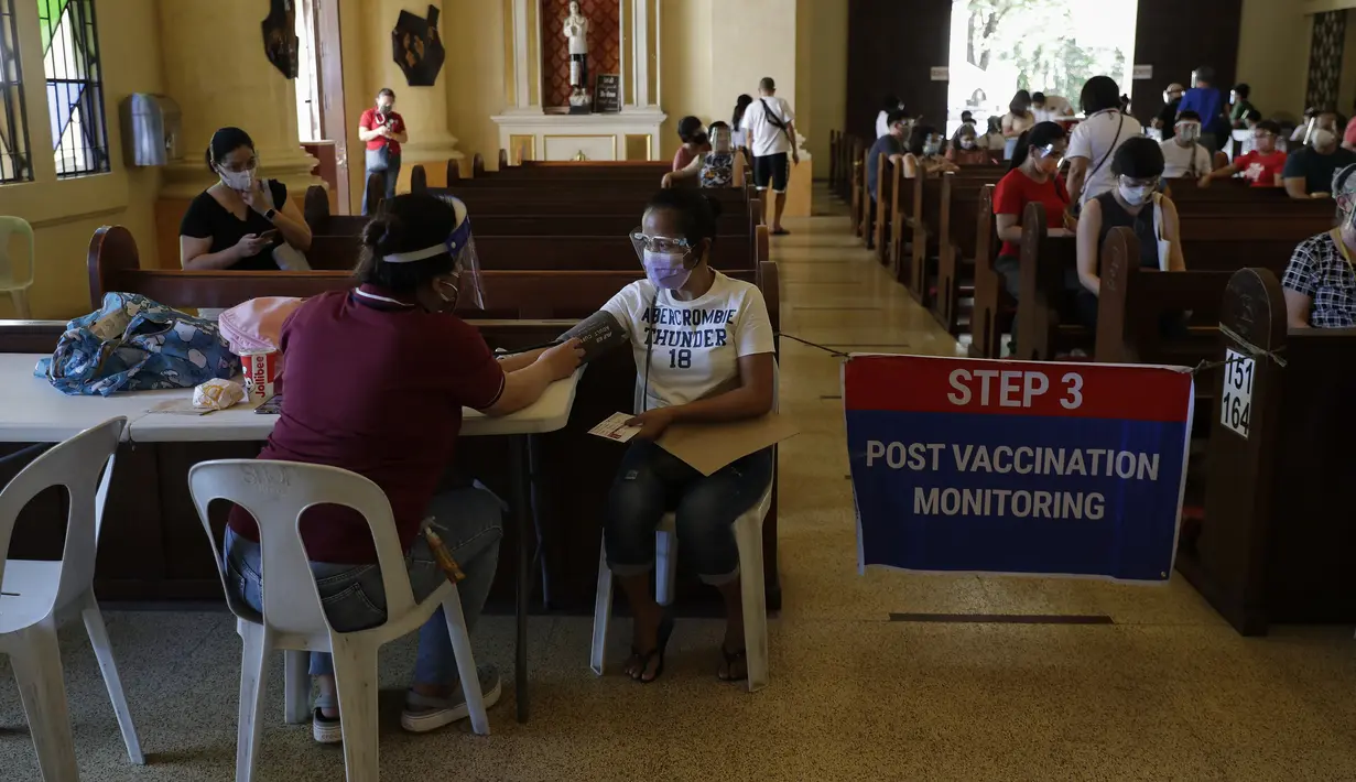 Petugas kesehatan memeriksa seorang perempuan setelah diinokulasi dengan vaksin COVID-19 AstraZeneca di dalam gereja Paroki Hati Kudus Yesus di Quezon City, Filipina, Senin (17/5/2021). Gereja itu digunakan untuk mempercepat proses vaksinasi kepada warga di daerah tersebut. (AP Photo/Aaron Favila)