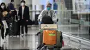 Penumpang mengenakan pakaian pelindung saat tiba di Bandara Internasional Hong Kong, Hong Kong (19/3/2020). Covid-19 yang menginfeksi lebih dari 200.000 orang terus menimbulkan kekhawatiran. (AFP/Anthony Wallace)