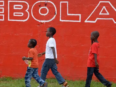 Sejumlah anak berjalan melewati dinding yang bertuliskan 'Ebola' di Monrovia, Liberia, 31 Agustus 2014. Liberia melarang para awak kapal untuk berlabuh di negara-negara yang rentan epidemi Ebola. (AFP PHOTO/DOMINIQUE FAGET)