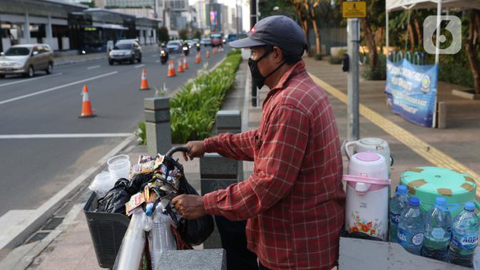 Pedagang minuman keliling bersiap melintasi lajur penyebrangan di Jalan Jenderal Sudirman, Jakarta, Rabu (23//9/2020). Menkeu Sri Mulyani Indrawati memastikan ekonomi nasional resesi pada kuartal III-2020. Kondisi ini akan berdampak pada pelemahan daya beli. (Liputan6.com/Helmi Fithriansyah)