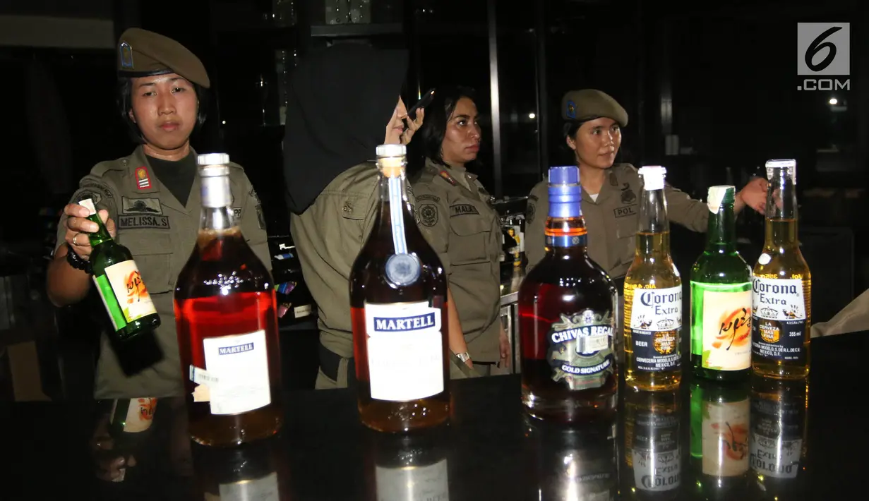 Petugas Satpol PP wanita mengamankan sejumlah botol minuman keras di Sense Karaoke, Mangga Dua Square, Jakarta, Kamis (19/4). (Liputan6.com/Arya Manggala)