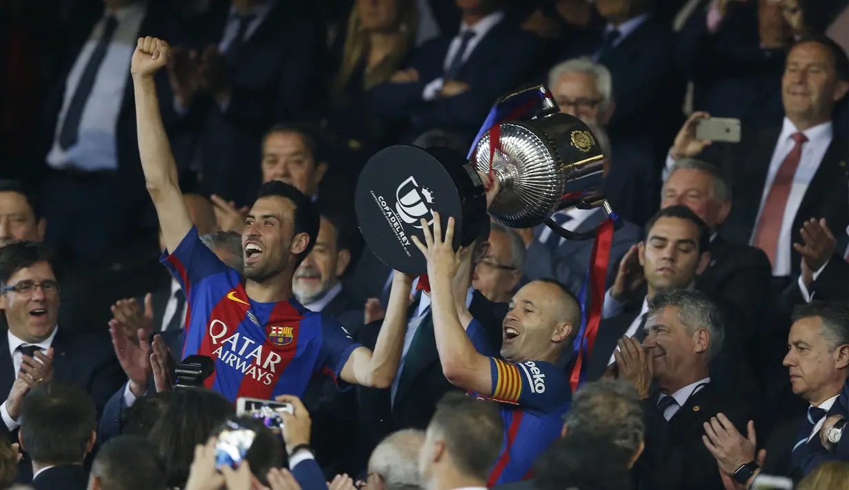 Kapten Barcelona, Andres Iniesta, bersama Sergio Busquets menerima trofi Copa Del Rey usai mengalahkan Alaves di Stadion Vicente Calderon, Madrid, Sabtu (27/5/2017). Barcelona menang 3-1 atas Alaves. (AP/Francisco Seco)