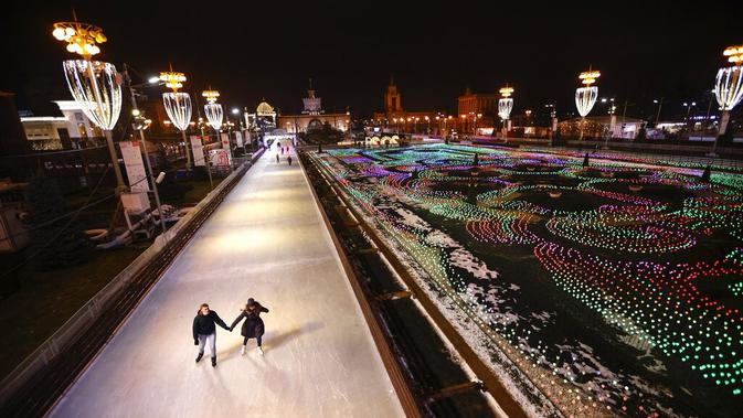 Dua orang berseluncur saat pembukaan arena seluncur es di VDNKh (Pameran Prestasi Ekonomi Nasional), Moskow, Rusia, Jumat (27/11/2020). Area tersebut terbuat dari lapisan es buatan lebih dari 20.000 meter persegi. (AP Photo/Alexander Zemlianichenko)