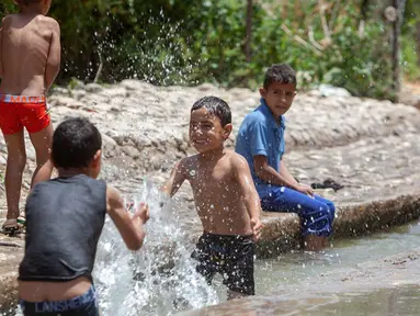 Anak-anak Palestina menikmati waktu bermain di sebuah mata air alami di tengah gelombang panas di Kota Jericho, Tepi Barat, (18/5/2020). (Xinhua/Luay Sababa)