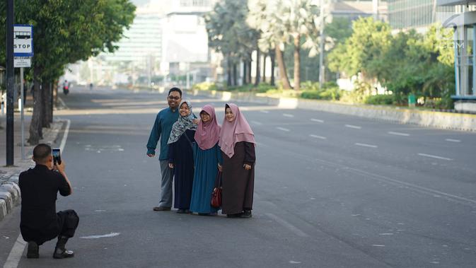 Warga berfoto di tengah Jalan MH Thamrin, Jakarta, Rabu (5/6/2019). Banyaknya warga Ibu Kota yang mudik ke kampung halaman untuk merayakan Hari Raya Idul Fitri membuat jalan protokol terpantau lengang. (Liputan6.com/Immanuel Antonius)