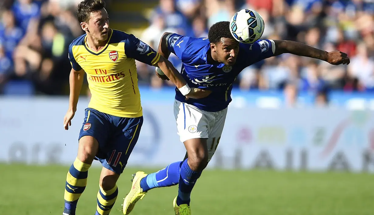 Pemain depan Arsenal, Mesut Ozil (kiri), menahan pergerakan bek Leicester City, Liam Moore, dalam laga lanjutan Liga Primer Inggris 2014-2015 di Stadion King Power, (31/8/2014). (REUTERS/Dylan Martinez)
