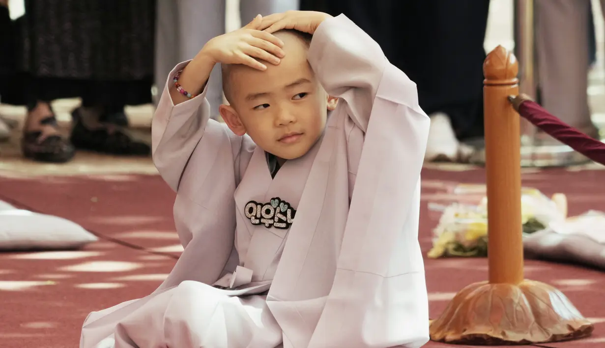 <p>Ekspresi biksu cilik yang memegangi kepalanya usai dicukur dalam sebuah acara kebaktitan di Kuil Jogye di Seoul, Korea Selatan, Selasa, 9 Mei 2023. (AP Photo/Ahn Young-joon)</p>