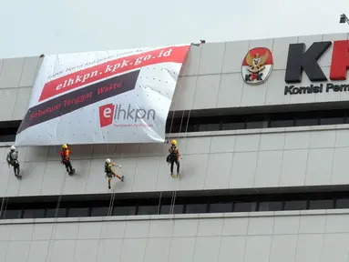Aktivis membentangkan spanduk raksasa dengan cara repling turun dari gedung C Komisi Pemberantasan Korupsi (KPK) di Jakarta, Senin (26/3). Spanduk tersebut bertuliskan "Berani Lapor Hebat!". (Merdeka.com/Dwi Narwoko)