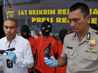 Kasat Reskrim Polres Metro Jakarta Selatan AKBP Audie Latuheru (kiri) menunjukkan barang bukti senjata api saat rilis kasus pencurian dengan kekerasan,di Jakarta, Rabu (25/11). Polisi berhasil mengamankan empat pelaku. (Liputan6.com/Gempur M Surya)