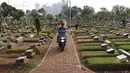 Dua anak menggendarai motor di sekitar TPU Karet Bivak, Jakarta, Kamis (26/7). Wagub DKI Jakarta Sandiaga Uno menyatakan Pemprov DKI akan mencari dan memerbanyak area TPU di Ibukota. (Liputan6.com/Immanuel Antonius)