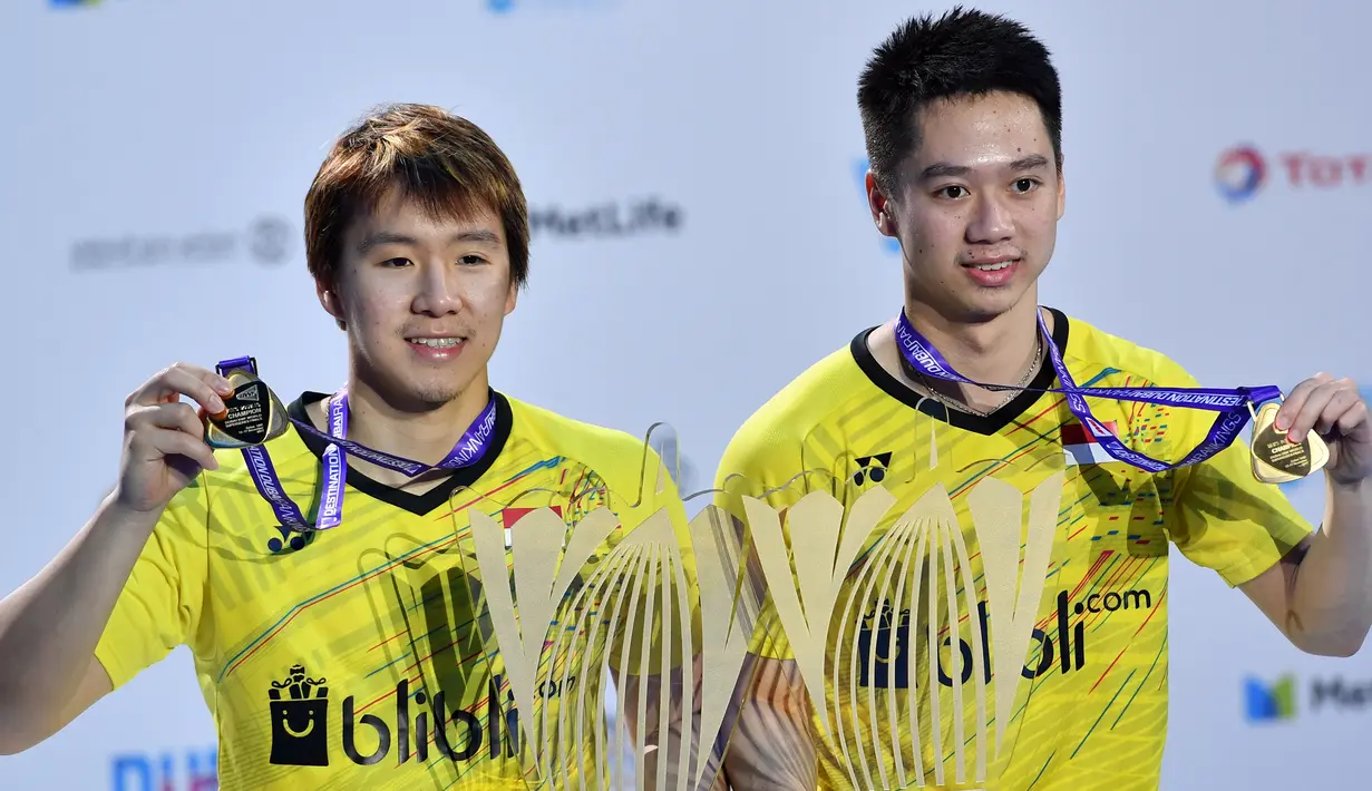 Pebulutangkis ganda putra Marcus Fernaldi Gideon dan Kevin Sanjaya Sukamuljo menunjukkan medali turnamen BWF Dubai Super Series Finals 2017, Minggu (17/12). Marcus/Kevin mempecundangi pasangan Tiongkok Zhang Nan/Liu Cheng 21-16 21-15 (GIUSEPPE CACACE/AFP)
