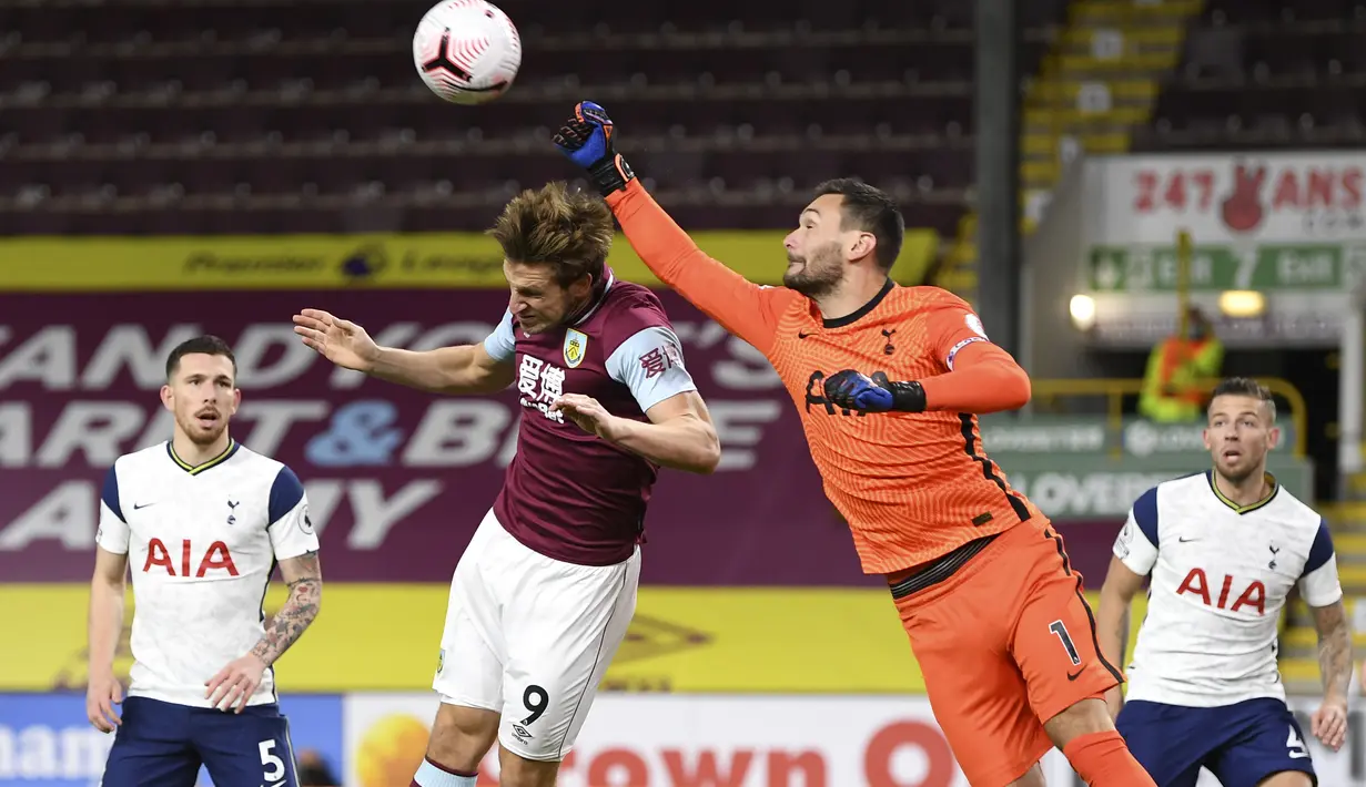 Kiper Tottenham Hotspur, Hugo Lloris meninju bola saat pemain Burnley Chris Wood berusaha menyundul bola pada pertandingan lanjutan Liga Inggris di stadion Turf Moor, Burnley, Inggris, Senin (26/10/2020). Tottenham menang tipis 1-0 atas Burnley. (Michael Regan/Pool via AP)