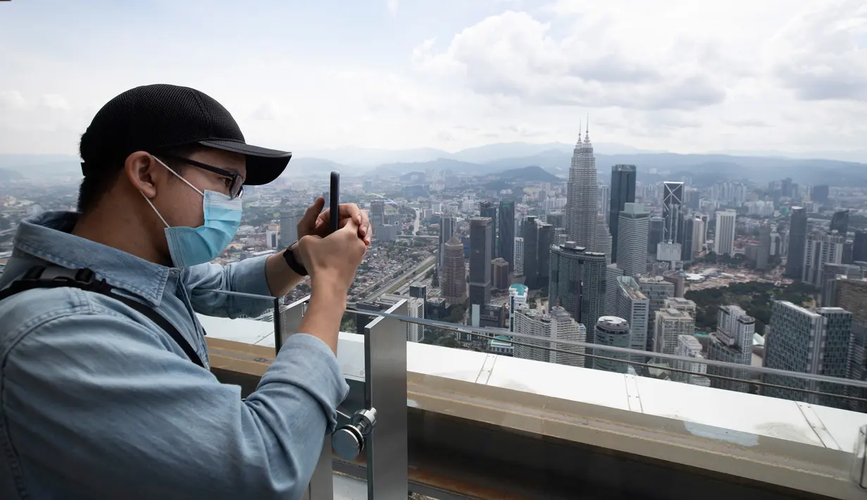 Seorang turis dengan mengenakan masker mengambil gambar dari dek obseravsi di Menara Kuala Lumpur di Kuala Lumpur, Rabu (1/7/2020). Malaysia memasuki pelonggaran Perintah Kontrol Gerakan (MCO) setelah tiga bulan pembatasan karena virus corona Covid-19. (AP Photo/Vincent Thian)