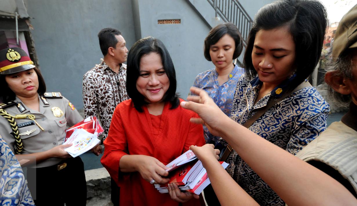 Iriana Jokowi membagikan buku kepada warga di Lapangan Bedeng, Pisangan Baru, Jakarta, Selasa (8/9/2015). Kedatangan Presiden Jokowi untuk memberikan sejumlah paket sembako. (Liputan6.com/Helmi Fithriansyah)