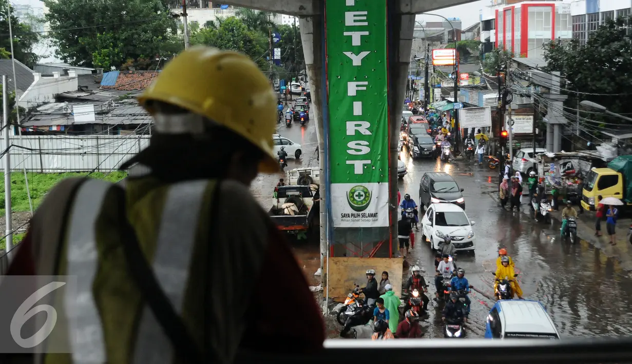 Pekerja proyek mengamati situasi Jalan Ciledug Raya dekat perempatan Seskoal, Jakarta, Jumat (11/11). Hujan deras diringi petir kembali melanda Jakarta mengakibatkan genangan air di beberapa titik. (Liputan6.com/Helmi Fithriansyah)