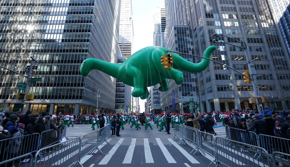 Balon Dino melayang di atas kawasan Sixth Avenue selama Parade Macy's Thanksgiving Day di New York, Kamis (22/11). Balon raksasa berbentuk ikon-ikon kartun terkenal menghiasi gelaran yang digelar untuk ke-92 tersebut. (Don EMMERT / AFP)
