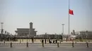 Bendera nasional China berkibar setengah tiang di Lapangan Tiananmen selama peringatan nasional tiga menit untuk memperingati orang yang meninggal dalam wabah coronavirus COVID-19, di Beijing (4/4/2020). (AFP/Leo Ramirez)