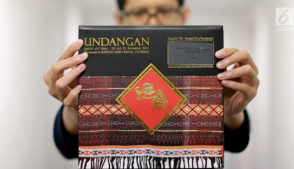Seorang pria memperlihatkan undangan acara adat ngunduh mantu Muhammad Bobby Nasution dan Kahiyang Ayu di Medan, Senin (20/11). Undangan adat sangat kental dengan ciri khas ulos yang didominasi warna merah dan hitam. (Liputan6.com/Johan Tallo)