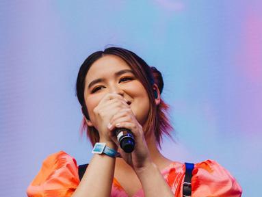 Penampilan Stephanie Poetri di panggung Head In The Clouds (HITC) Jakarta. Penyanyi besutan label musik 88rising ini tampil dengan dress cantik berwarna oranye. (Instagram/@hitcjakarta)