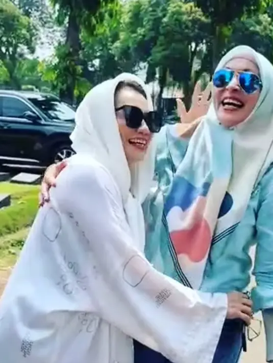 Reza Artamevia ke makam Adjie Massaid mengenakan baju oversized putih lengan panjang dibalut kerudung warna senada. Pelantun “Satu Yang Tak Bisa Lepas” pakai kaca mata hitam. Sementara Puteri Indonesia 2001 mengenakan hijab biru motif abstrak yang dipadukan dengan busana mulim warna senada dan kacamata. Keduanya berpeluk di permakaman Jeruk Purut Jakarta. (Foto: Dok. Instagram @rezaartameviaofficial)