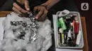 Seto Krisna Putra menyelesaikan pembuatan miniatur robot dari sampah korek gas di Kantor Sudin LH Jakarta Timur, Minggu (20/2/2022). Seto membuat miniatur robot sejak 2006 untuk mengajak dan meningkatkan minat generasi muda berkreativitas dari barang bekas di sekitar. (merdeka.com/Iqbal S Nugroho)