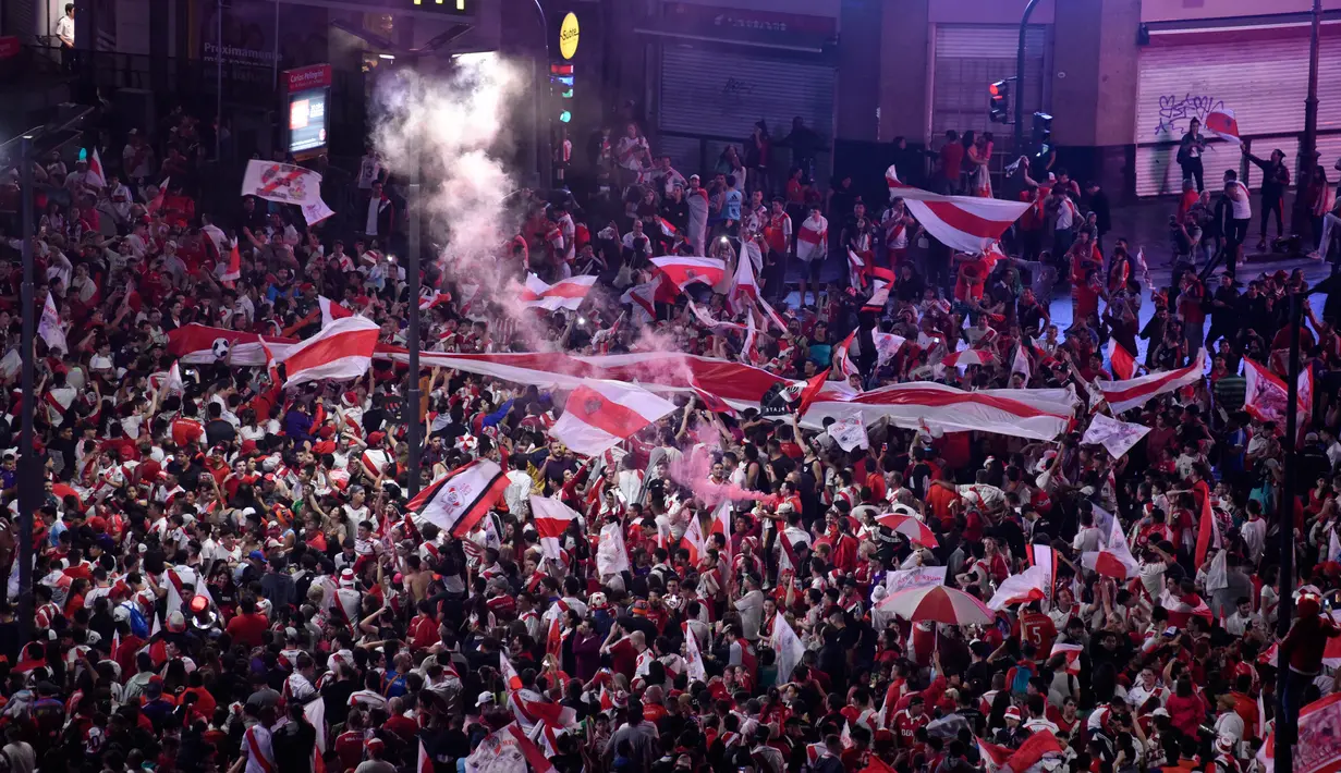 Suporter River Plate mengibarkan bendera saat merayakan gelar juara Copa Libertadores di Obelisk, Buenos Aires, Argentina, Minggu (9/12). River Plate merebut gelar juara Copa Libertadores usai menaklukkan Boca Juniors. (AP Photo/Gustavo Garello)