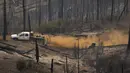 Seorang anggota kru pendukung buldoser mengemudi melalui hutan yang hancur di Oak Fire dekat Mariposa, California, Amerika Serikat, 26 Juli 2022. Api Washburn telah mengancam pohon sequoia raksasa di Hutan Mariposa. (DAVID MCNEW/AFP)