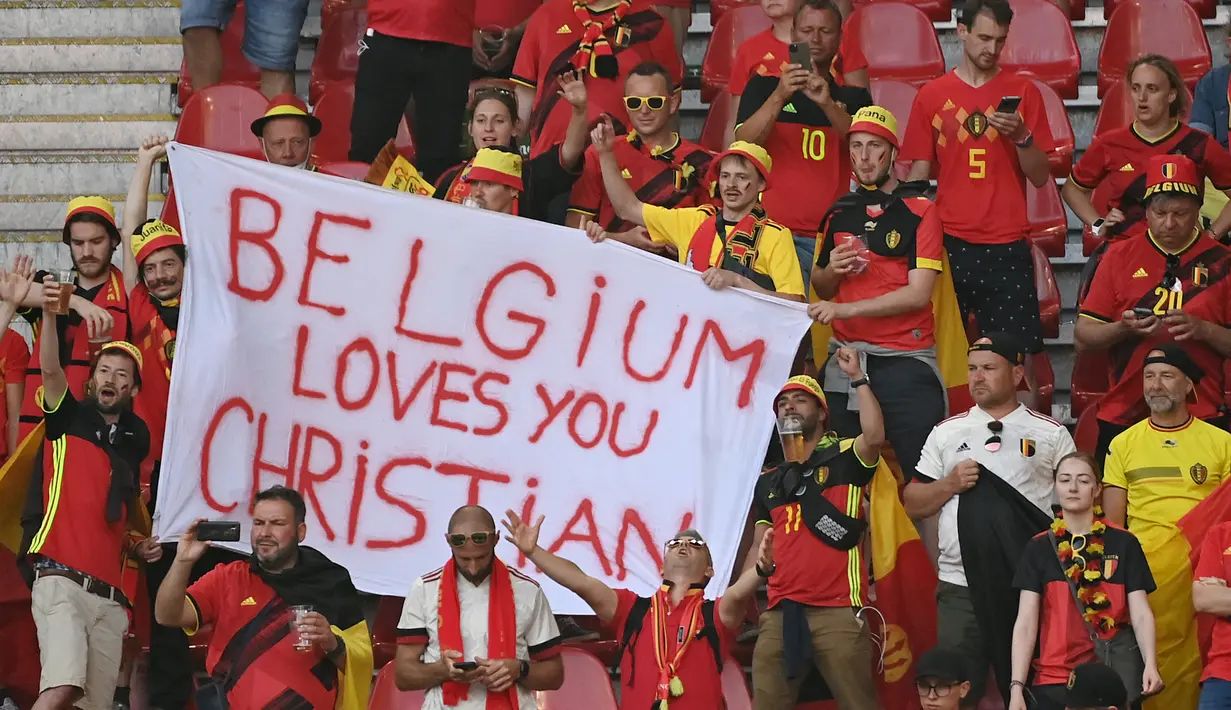 Suporter timnas Belgia dengan spanduk dan pesan dukungan untuk gelandang Denmark, Christian Eriksen menunggu dimulainya pertandingan Grup B EURO 2020 antara Denmark dan Belgia di Stadion Parken di Kopenhagen, Kamis (17/6/2021). (Jonathan NACKSTRAND / POOL / AFP)
