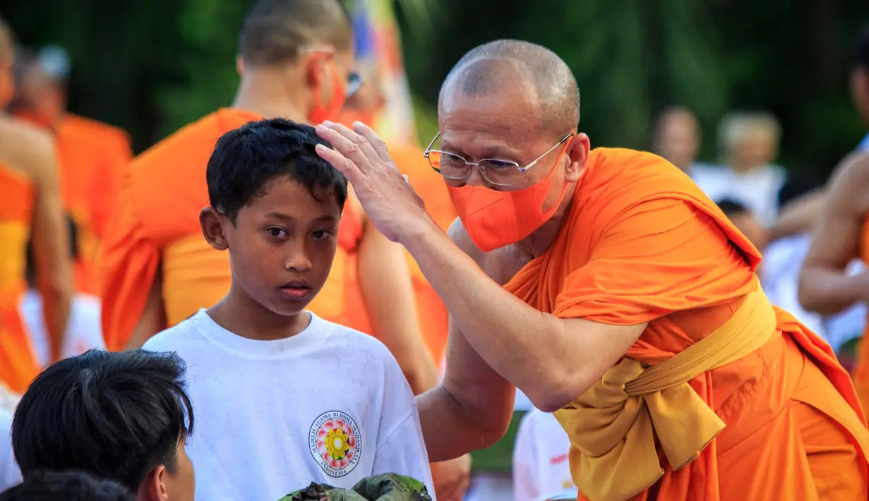 Foto yang diambil pada 17 Desember 2023 ini menunjukkan para biksu Buddha sedang mencukur rambut seorang samanera (calon biksu) muda. (DEVI RAHMAN/AFP)