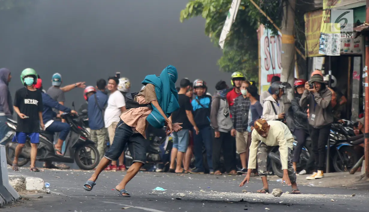 Massa melempar batu ke arah aparat keamanan saat terjadi bentrok di kawasan Slipi, Jakarta Barat, Rabu (22/5/2019). Kerusuhan ini buntut aksi 22 Mei menolak hasil Pilpres 2019 yang diumumkan oleh KPU. (Liputan6.com/Gempur Muhammad Surya)