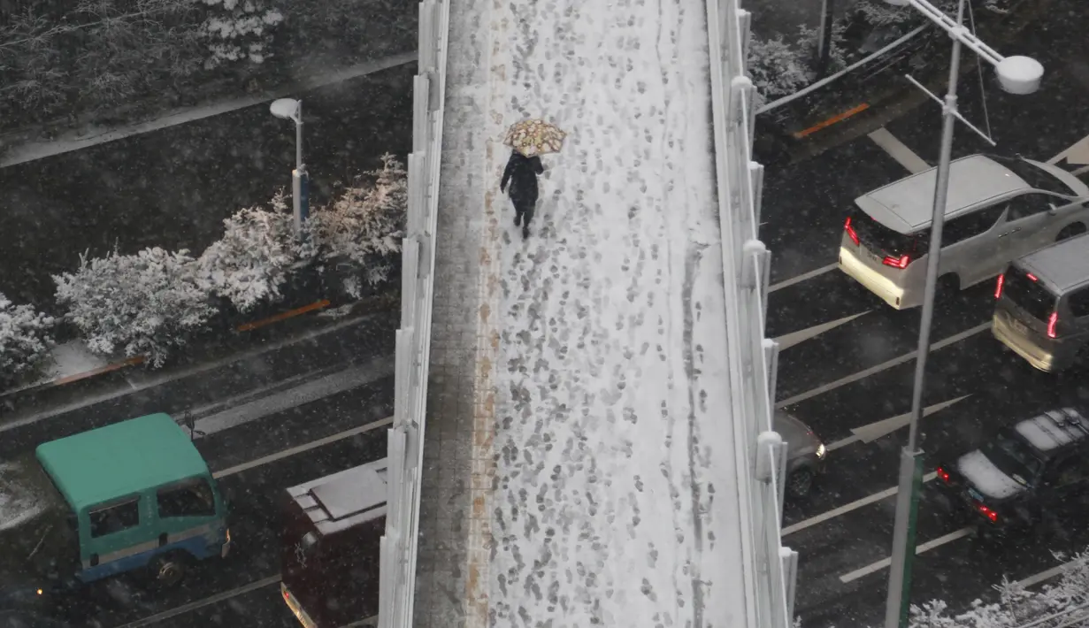 Seseorang berjalan di atas salju di Tokyo, Kamis (6/1/2022). Dalam 24 jam hingga Jumat siang, salju diperkirakan mencapai 10 cm di daerah pegunungan dan hingga 5 cm di dataran wilayah Kanto, yang mencakup 23 distrik di pusat kota Tokyo. (AP Photo/Koji Sasahara)