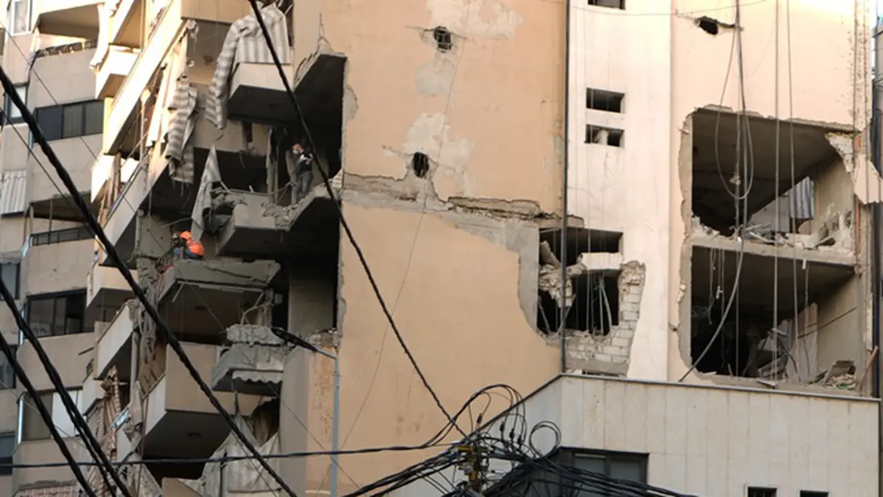 Para petugas pertahanan sipil memeriksa kerusakan setelah sebuah gedung apartemen terkena serangan udara Israel di Dahiyeh, pinggiran selatan Beirut, Lebanon, Minggu (23/11/2025).