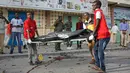 Petugas medis mengevakuasi jasad warga sipil dari lokasi ledakan bom mobil di dekat pos pemeriksaan parlemen dan Kementerian Dalam Negeri di Ibu Kota Somalia, Mogadishu, Minggu (25/3). Serangan menewaskan empat orang. (AP/Farah Abdi Warsameh)