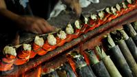 Pekerja mengambil lemang bambu di sentra pembuatan lemang kawasan Kramat Raya, Senen, Jakarta, Jumat (17/6). Pembuatan lemang pada Ramadan meningkat lebih dari 300 persen dibanding hari biasa hingga mencapai 500 buah per-hari (Liputan6.com/Gempur M Surya)