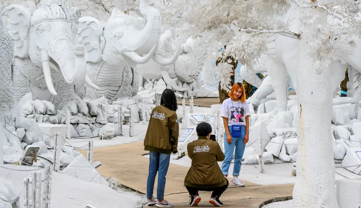 Foto pada yang diabadikan 2 September 2020 memperlihatkan pengunjung berfoto di depan patung dari pasir putih yang menyerupai es di taman "Frost Magical Ice of Siam", di luar Pattaya, Thailand. (Photo by Mladen ANTONOV / AFP)