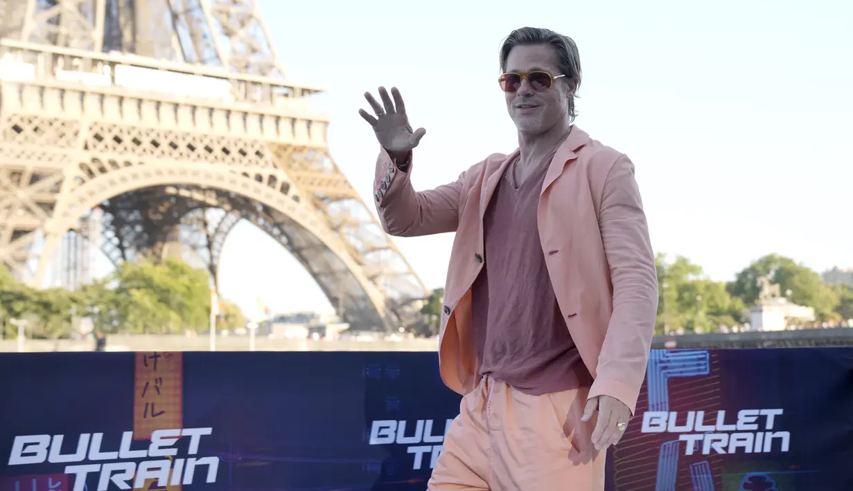 <p>Aktor Hollywood Brad Pitt melambai saat sesi pemotretan untuk film 'Bullet Train' di Paris, Prancis, Sabtu (16/7/2022). Aktor berusia 58 tahun tersebut tampil kasual dengan blazer oranye cerah, celana panjang berwarna serasi, dan T-shirt. (AP Photo/Christophe Ena)</p>