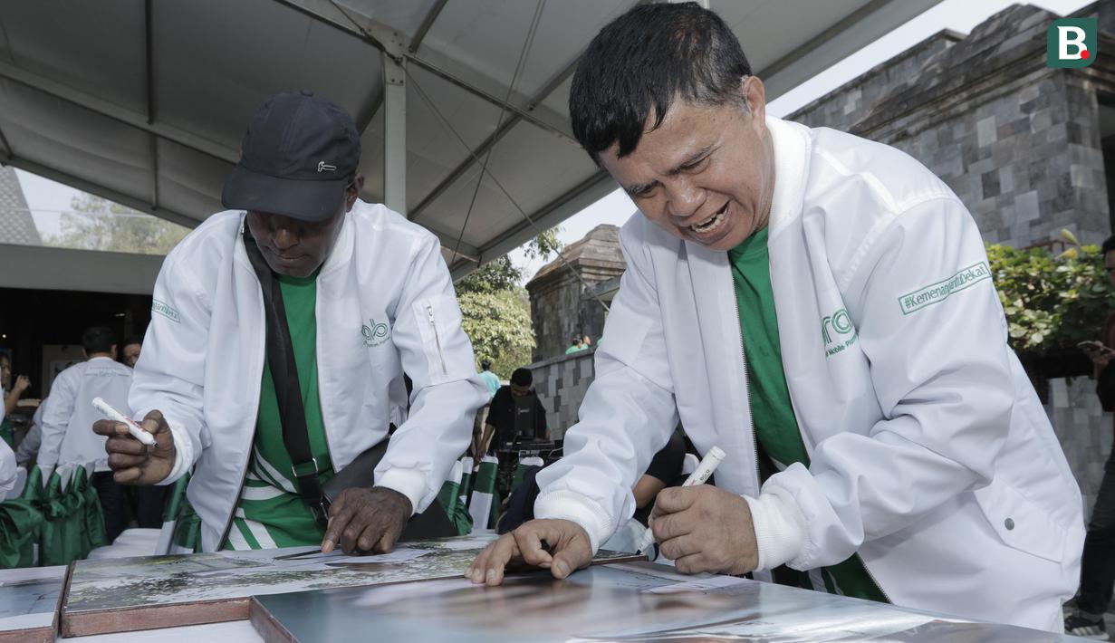 Legenda tinju Indonesia, Ellyas Pical, menandatangani foto saat pameran foto di Yogyakarta, Rabu (18/7/2018). Pameran foto legenda olahraga Indonesia tersebut sekaligus peluncuran kampanye Grab "Kemenangan itu Dekat". (Bola.com/M Iqbal Ichsan)