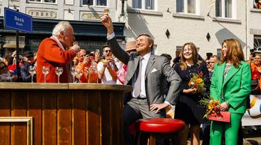 Raja Belanda Willem-Alexander (kiri) bersulang dengan jeruk pahit diapit oleh Putri Ariane (kedua dari kanan) dan Putri Alexia (kanan) saat menghadiri perayaan Hari Raja di Maastricht, Belanda, Rabu (27/4/2022). Setelah dua tahun hening karena pandemi COVID-19, Belanda kembali merayakan Hari Raja seperti biasa. (Remko de Waal/ANP/AFP)