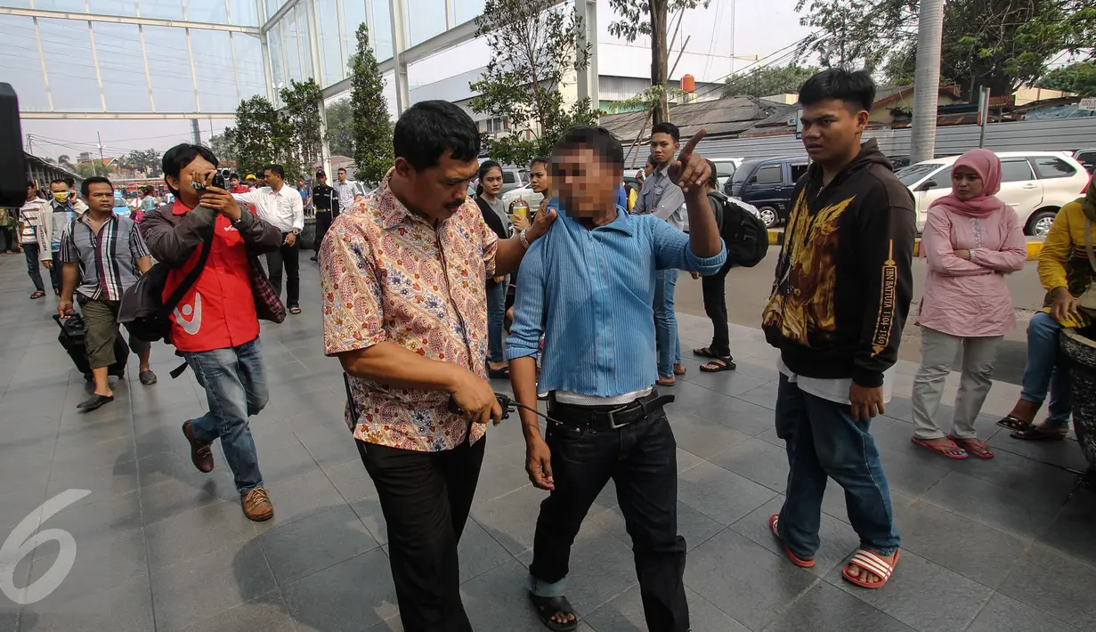 Petugas dari Polsek Senen menangkap seorang calo tiket kereta api di Stasiun Senen, Jakarta, Senin (29/6/2015). Razia tersebut dilakukan untuk mengamankan stasiun dari para calo yang merugikan calon penumpang. (Liputan6.com/Faizal Fanani) 