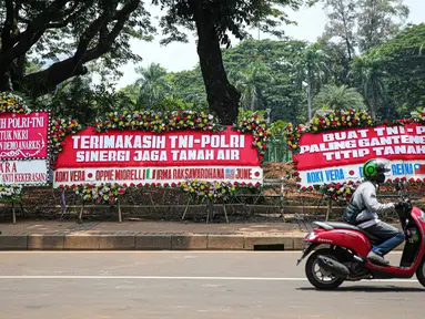 Kendaraan melintasi karangan bunga yang menghiasi kawasan Patung Kuda, Jakarta, Kamis (15/10/2020). Karangan bunga tersebut merupakan apresiasi masyarakat kepada TNI-Polri yang telah menjaga keamanan saat demo. (Liputan6.com/Faizal Fanani)