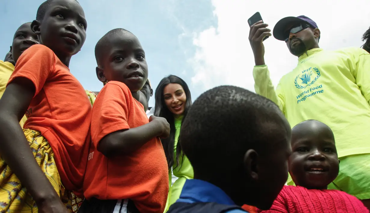 Rapper AS, Kanye West dan istrinya, Kim Kardashian mengunjungi anak-anak yatim di Kampung Anak UWESCO di Masulita, Uganda, Selasa (16/10). Ketika di sana, Kanye West membagikan ratusan pasang Yeezy Boost 350 V2s kepada anak-anak. (STRINGER / AFP)