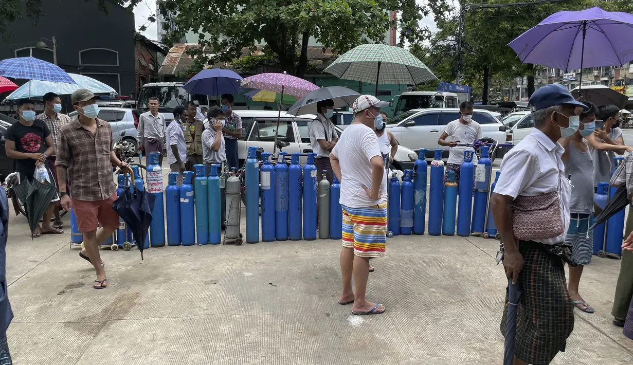 Orang-orang mengantre dengan tabung oksigen mereka di luar stasiun pengisian oksigen di kota Pazundaung di Yangon, Myanmar, Minggu (11/7/2021). Para pejabat mengatakan Myanmar mengalami lonjakan kasus COVID-19, memicu kelangkaan pasokan oksigen yang sangat dibutuhkan pasien. (AP Photo)