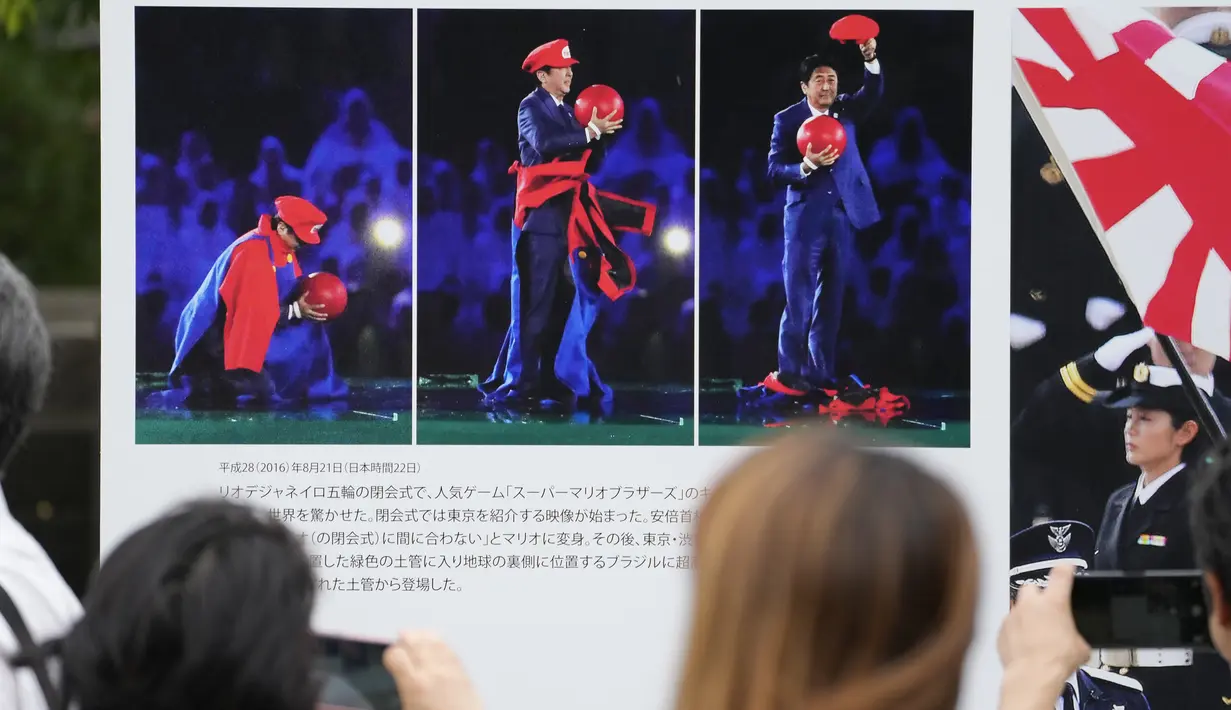 Orang-orang menonton gambar mantan Perdana Menteri Jepang Shinzo Abe sebelum berdoa di kuil Zojoji di Tokyo, Sabtu, 8 Juli 2023. (AP Photo/Shuji Kajiyama)