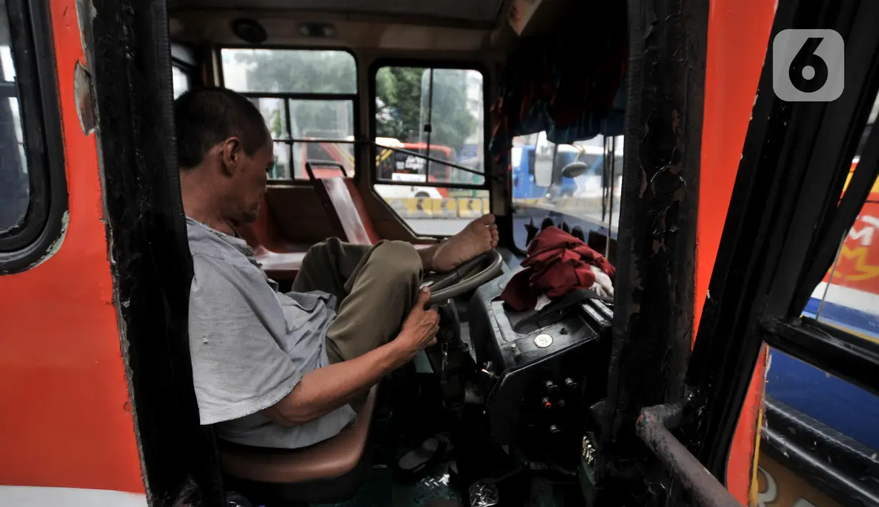 Sianipar (62) tertidur di bangku kemudi saat mengetem di Terminal Blok M, Jakarta, Rabu (13/11/2019). Kakek dua cucu ini mengaku pernah hanya mengantongi uang Rp 20 ribu dari seharian menarik Metromini 69 jurusan Ciledug-Blok M. (merdeka.com/Iqbal Nugroho)