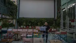 Seorang pegawai menata kursi sebelum pemutaran film di bioskop terbuka Palace, Athena, Yunani, 10 Agustus 2020. Pandemi COVID-19 memaksa bioskop terbuka dipersingkat sehingga menyebabkan penurunan jumlah penonton. (ANGELOS TZORTZINIS/AFP)