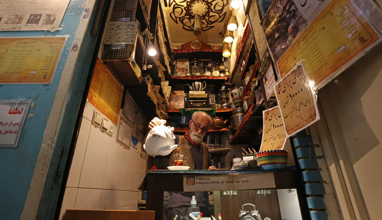 Pemilik Kazem Mabhutian (63) menyajikan teh di kedai teh terkecil dan tertua di gang Grand Bazaar di ibukota Iran, Teheran (20/9/2021).  Di sela-sela menuangkan segelas teh untuk pelanggannya, Kazem memberi tahu kisah seabad tentang Rumah Teh Haj Ali Darvish dengan bangga. (AFP/Atta Kenare)
